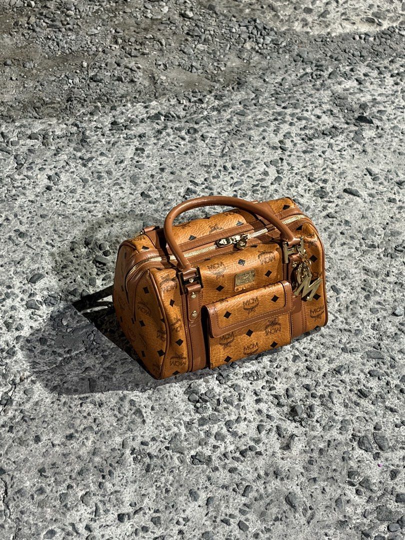 MCM Boston Bag (Category: Luxury Bags & Wallets) located in Manila. Submitted by lancephili44479 (Listing ID 1439197464, Image 1). Description: - Authentic MCM Boston bag - Features the iconic MCM logo pattern - Top handle and front pocket - Includes a gold-tone charm - Suitable for everyday use or special occasions.