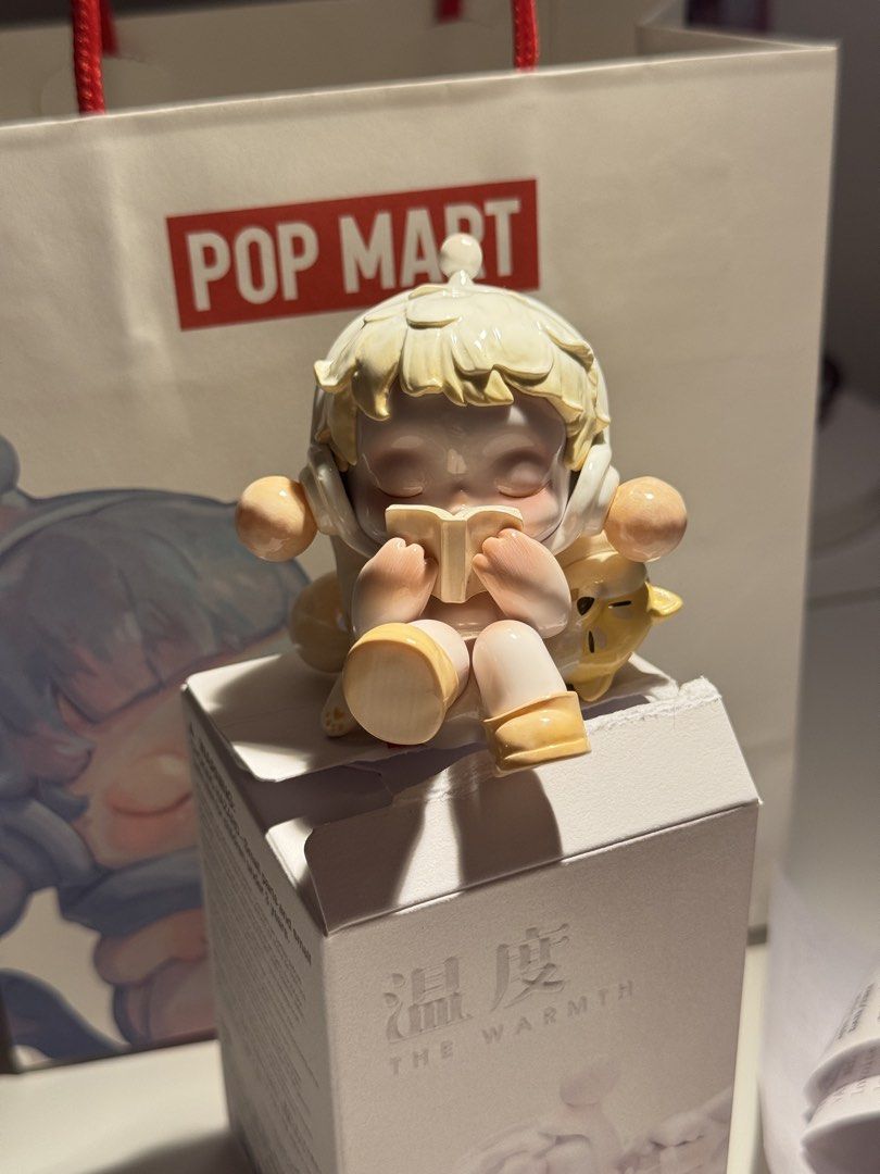 Pop Mart The Warmth Series Figure (Category: Designer & Blind Box Toys) located in Mandaluyong City. Submitted by _elyscntmh (Listing ID 1439093130, Image 1). Description: - Pop Mart The Warmth Series figure - Features a cute character reading a book - Light yellow color scheme - Sits on a box with "The Warmth" printed on it - Includes original packaging: Topbox & Foil Insealed. With paperbag & card -Opened 5-20-26 -RFS: Duplicate .