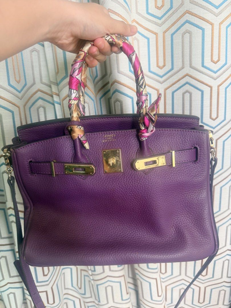 Purple Leather Handbag with Scarf Handle (Category: Shoulder Bags) located in Taguig. Submitted by che_f25 (Listing ID 1439094832, Image 1). Description: - Purple leather handbag - Gold-tone hardware - Top handle with patterned scarf - Detachable shoulder strap - Multiple interior compartments - Zippered pocket inside - Structured shape - Flap closure with buckle details - Textured leather finish.
