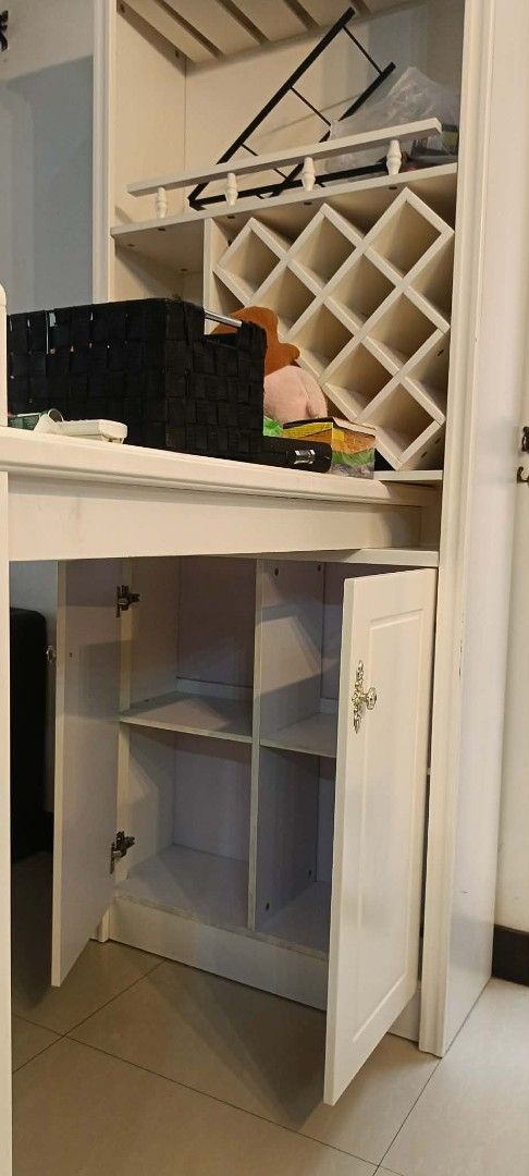 White Wooden Bar Cabinet (Category: Shelves, Cabinets & Racks) located in Pasig City. Submitted by kimjose (Listing ID 1439242076, Image 2). Description: - Elegant white wooden bar cabinet - Includes wine rack and glass holders - Features a pull-out counter - Cabinet doors with interior shelving - Ideal for storing beverages and barware - Perfect for home entertainment.