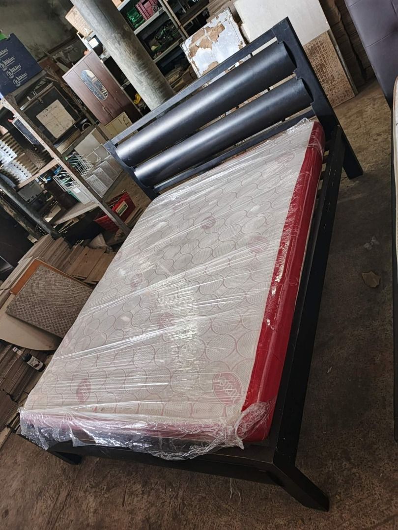 Wooden Bed Frame with Mattress (Category: Bed Frames & Mattresses) located in San Pedro. Submitted by cgi.saversplustrading (Listing ID 1439083204, Image 3). Description: - Black wooden bed frame - Includes mattress (wrapped in plastic) - Unique headboard design - Sturdy and well-built construction - Ideal for bedroom use.