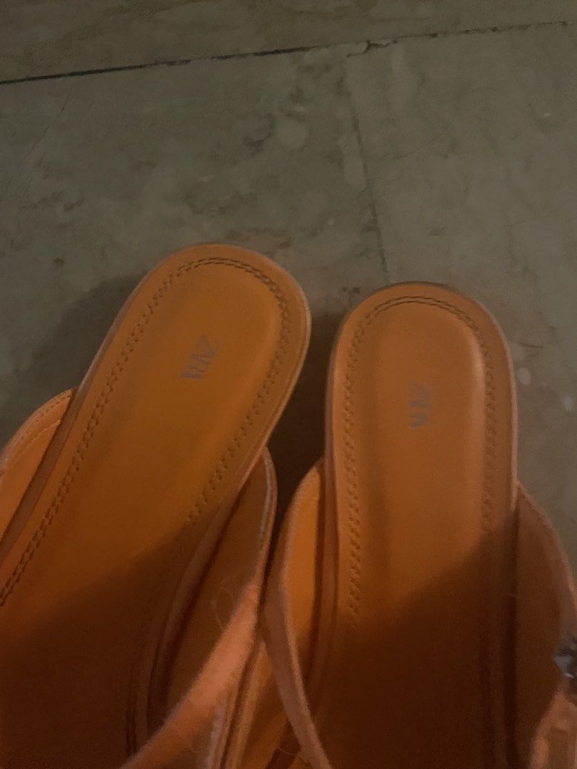 Zara Orange Square Toe Mules (Category: Flats & Sandals) located in Quezon City. Submitted by deadmit (Listing ID 1439069783, Image 3). Description: These Zara mules feature a square toe design and an orange color. They have a strap around the ankle with a buckle closure. The shoes have a low heel and the Zara logo is visible on the insole. The soles are black..