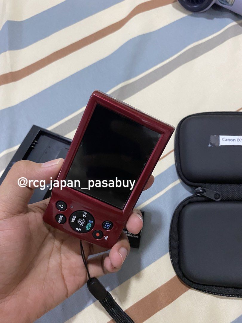 Canon IXY 130 Digital Camera (Category: Cameras) located in Legazpi City. Submitted by rcg.japan_pasabuy (Listing ID 1439381644, Image 3). Description: -₱8.8k sure buyer - Canon IXY 130 digital camera (red) - Includes charger, battery, and carrying case - Attached wrist strap - Displays 'No memory card' message - Features zoom lens and function buttons - Compact size.