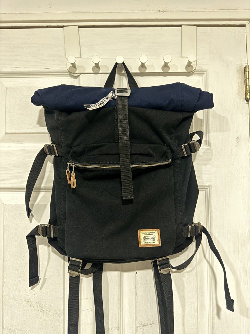 Coleman Journey Roll Top Backpack (Category: Backpacks) located in Cavite. Submitted by bertolomee (Listing ID 1439357430, Image 1). Description: Coleman Journey Roll Top Backpack features a roll-top design with adjustable straps and multiple compartments. It has a front zippered pocket and a padded back panel for comfort. The backpack is black with a navy blue top and includes the Coleman logo on the front..