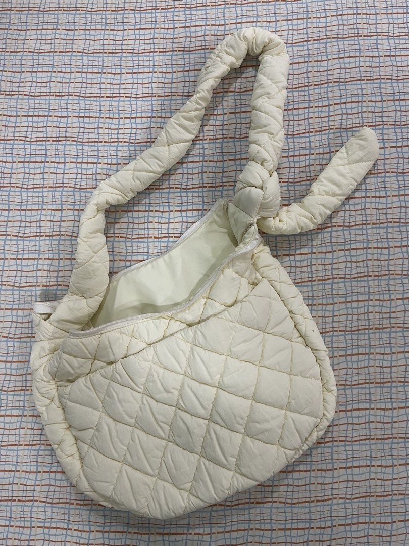 GU Puffer Cream Quilted Shoulder Bag (Category: Shoulder Bags) located in Quezon City. Submitted by ewyeung (Listing ID 1439308610, Image 1). Description: - Cream-colored quilted shoulder bag - Unique knotted strap design - Spacious interior - Zipper closure - Small interior pocket - Made of soft, padded material - Minor stain on exterior.