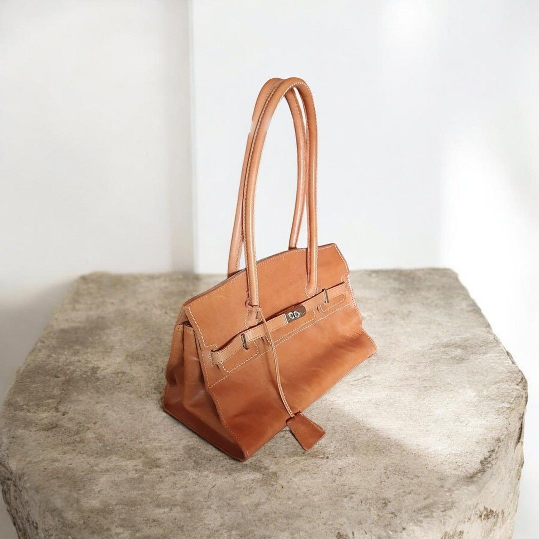 Leather Birkin Style Small Long Shoulder Bag (Category: Luxury Bags & Wallets) located in Davao. Submitted by REARY (Listing ID 1439417617, Image 3). Description: Elegant tan leather handbag with top handles. Features a flap closure with a silver-tone clasp and a small leather tag. The bag has a zippered pocket on the back and multiple interior compartments. The interior lining is a light beige fabric..
