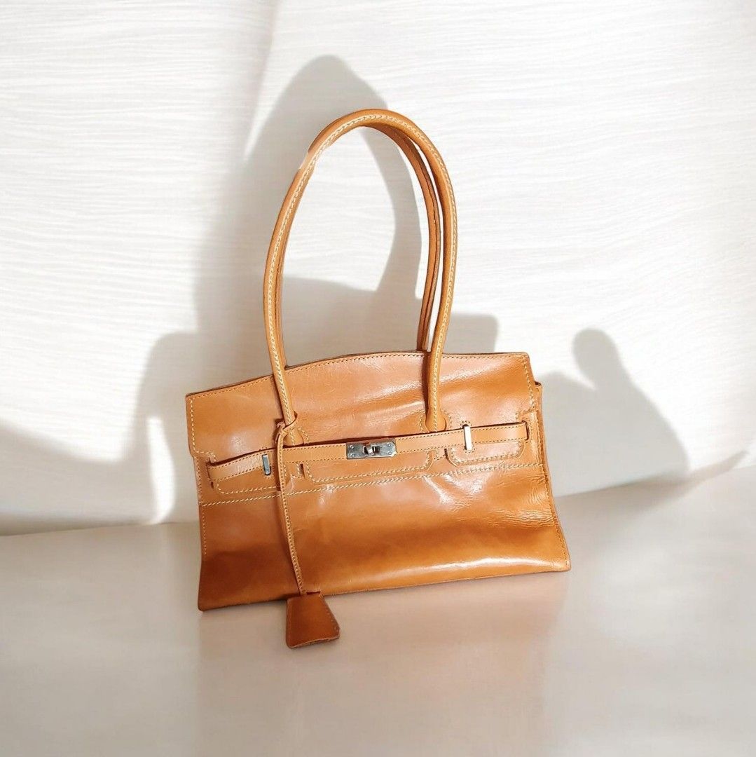 Leather Birkin Style Small Long Shoulder Bag (Category: Luxury Bags & Wallets) located in Davao. Submitted by REARY (Listing ID 1439417617, Image 1). Description: Elegant tan leather handbag with top handles. Features a flap closure with a silver-tone clasp and a small leather tag. The bag has a zippered pocket on the back and multiple interior compartments. The interior lining is a light beige fabric..