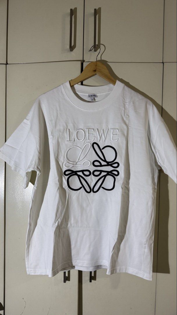 Loewe Embroidered Logo T-shirt (Category: Tshirts & Polo Shirts ) located in Quezon City. Submitted by mogsmogs (Listing ID 1439391678, Image 1). Description: - Loewe white t-shirt - Embroidered logo on front - Made in Portugal - 100% cotton - Crew neck - Short sleeves Dimes: 22 width x 27 length Rfs: nakatambak sa closet, tumaba ako.