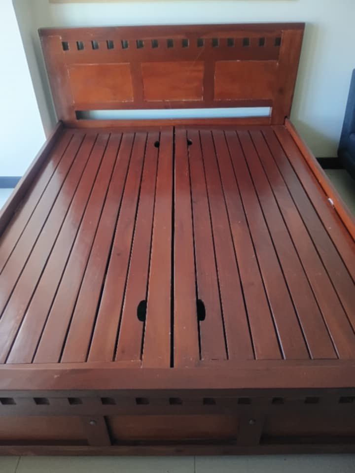 Mahogany Wooden Bed Frame with Storage (Category: Bed Frames & Mattresses) located in Makati City. Submitted by sheeca (Listing ID 1439335931, Image 2). Description: - Solid wood bed frame - Dark, rich finish - Decorative headboard design - Built-in storage with two doors - Slatted base for mattress support - Spacious storage compartments - there is a bit of discolouration on the storage compartment area - note pure mahogany wood - heavy duty bed