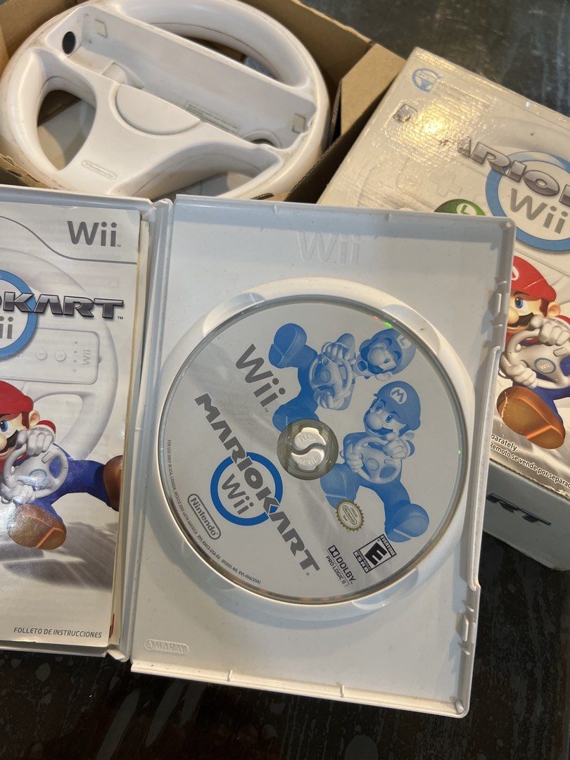 Mario Kart Wii with Steering Wheel (Category: Nintendo) located in Bacoor. Submitted by homergarage (Listing ID 1439298966, Image 2). Description: - Mario Kart Wii game for Nintendo Wii. - Includes game disc. - Comes with a white steering wheel accessory. - Features Mario and Luigi on the cover. - Box and steering wheel are white..