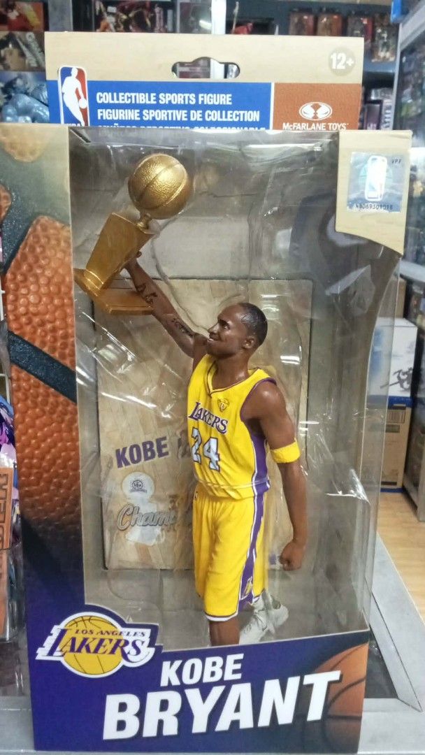 McFarlane NBA Kobe Bryant Lakers Champion JN (Category: Figurines & Statues) located in Manila. Submitted by robinshobbyshopph (Listing ID 1439302227, Image 1). Description: - Kobe Bryant collectible figure - Lakers jersey - Holding a trophy - Original packaging - Features NBA logo - "COLLECTIBLE SPORTS FIGURE" text on packaging - Pick up at Robin's Hobby shop, Shoppesville Plus, Greenhills - BPI deposit/online transfer or cash on pick up or GCas