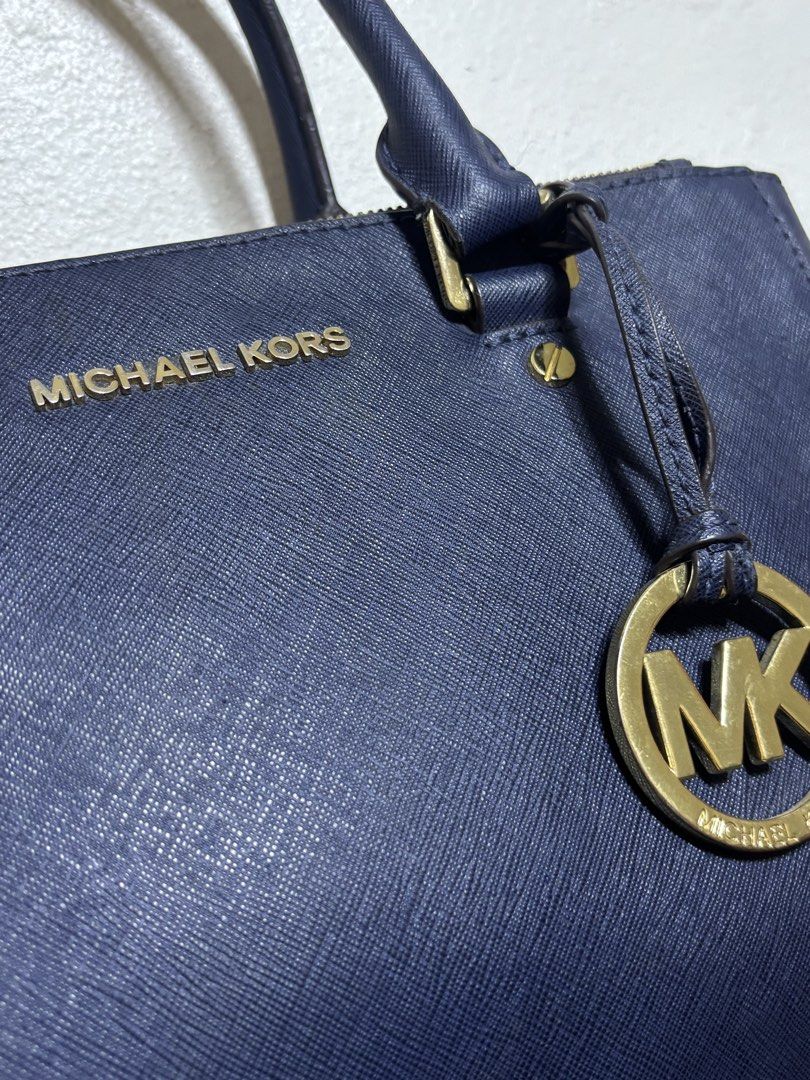 Michael Kors Navy Blue Satchel Bag (Category: Luxury Bags & Wallets) located in Aloran. Submitted by aezamirae (Listing ID 1439296525, Image 2). Description: - Authentic Michael Kors satchel bag - Navy blue color - Top handle and detachable shoulder strap - Gold-tone MK logo charm - Gold-tone hardware - Multiple interior compartments - Branded lining - Michael Kors logo on zippers Negotiable.