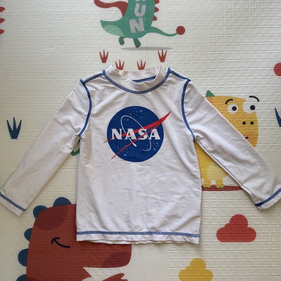 NASA Long Sleeve Rash Guard (Category: Babies & Kids Fashion) located in Davao. Submitted by taycodissimo_apparel (Listing ID 1439263895, Image 1). Description: - White long-sleeved rash guard - Features a NASA logo - Blue stitching details - Designed for sun protection - Perfect for water activities - Suitable for children.