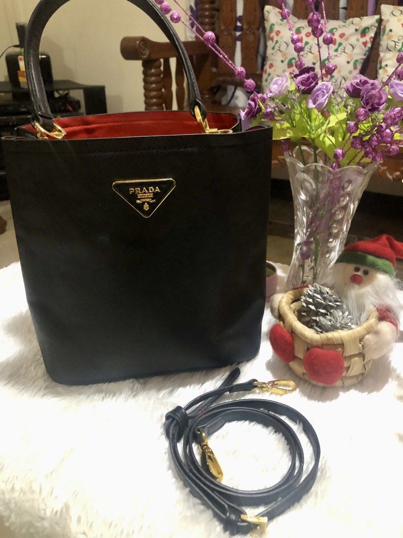 Prada Black Handbag with Red Interior (Category: Luxury Bags & Wallets) located in Meycauayan. Submitted by miletteaqu82717 (Listing ID 1439305000, Image 1). Description: - not guaranteed Prada handbag - Classic black exterior - Striking red interior - Gold Prada logo and hardware - Detachable black strap - Structured shape with top handles - Interior pocket with Prada label - no lock major flaw.