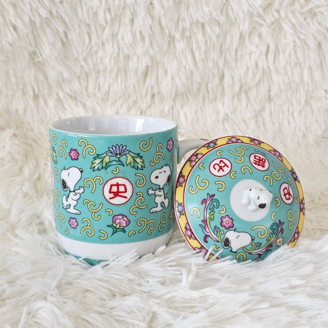 Snoopy Ceramic Mug with Lid (Category: Coffee & Tea Tableware) located in Taguig. Submitted by ljdm_22 (Listing ID 1439279517, Image 3). Description: - Snoopy ceramic mug with matching lid. - Features a charming Snoopy design. - Teal background with floral and Chinese character accents. - Lid has a Snoopy figure as a handle. - Includes a handle for easy grip. - Ideal for enjoying hot beverages..