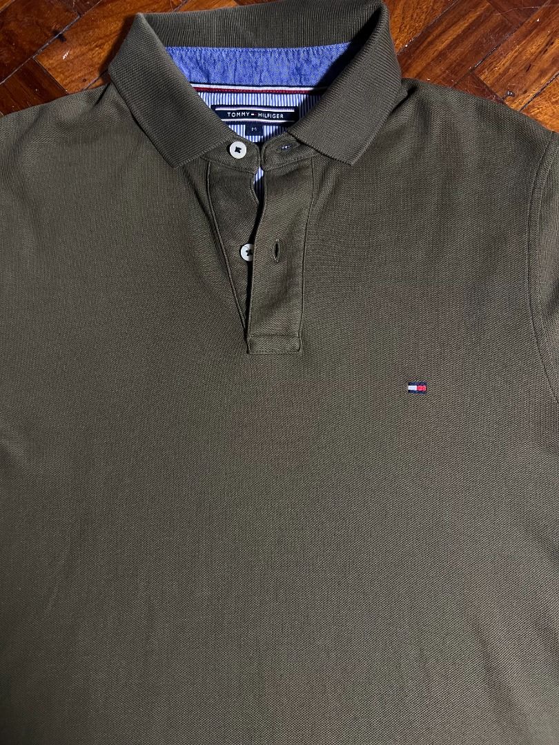 Tommy Hilfiger Polo Shirt (Category: Tshirts & Polo Shirts ) located in Quezon City. Submitted by don.fitss (Listing ID 1439345818, Image 2). Description: - Olive green Tommy Hilfiger polo shirt - Classic polo collar with blue and white striped inner lining - Short sleeves - Three-button placket - Tommy Hilfiger logo on chest - Made of textured fabric.
