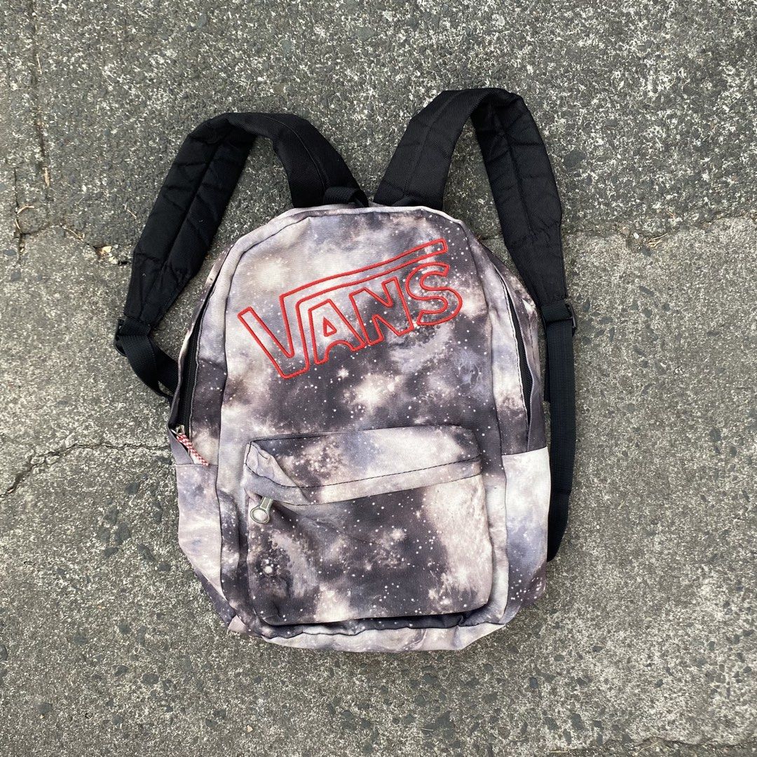 Vans Backpack (Category: Backpacks) located in Manila. Submitted by shi.vimn (Listing ID 1439253932, Image 1). Description: Vans backpack features a unique galaxy print. It has a front pocket and padded shoulder straps for comfort. The Vans logo is prominently displayed in red. It's a stylish and functional choice for carrying essentials..