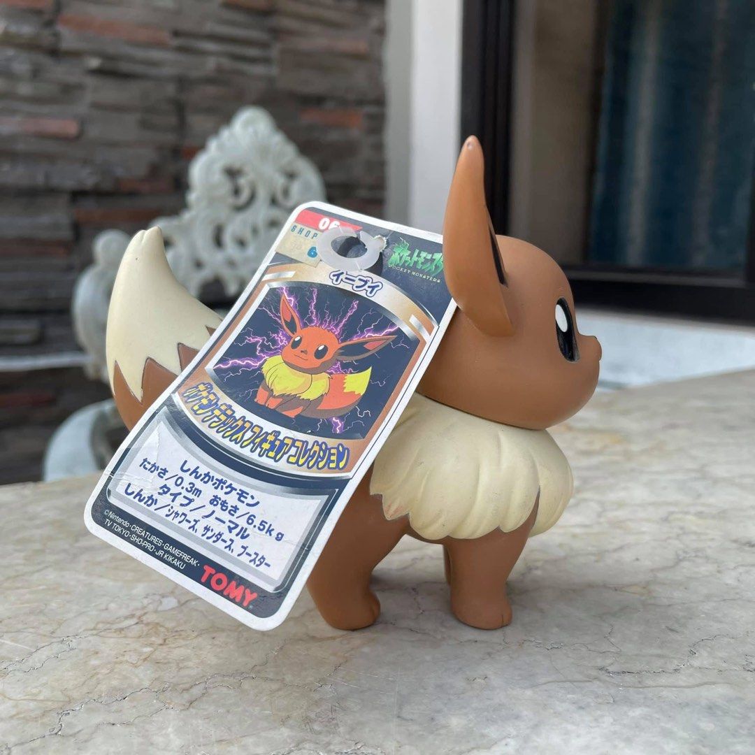 Vintage Tomy Pokemon Eevee Figure (Category: Figurines & Statues) located in Quezon City. Submitted by dangogow (Listing ID 1439346046, Image 2). Description: Tomy Pokemon Eevee figure. It has a brown body, cream-colored fur, and large ears. The figure comes with its original tag. The bottom of the figure has the year 1998 printed on it. It is a collectible item for Pokemon fans..