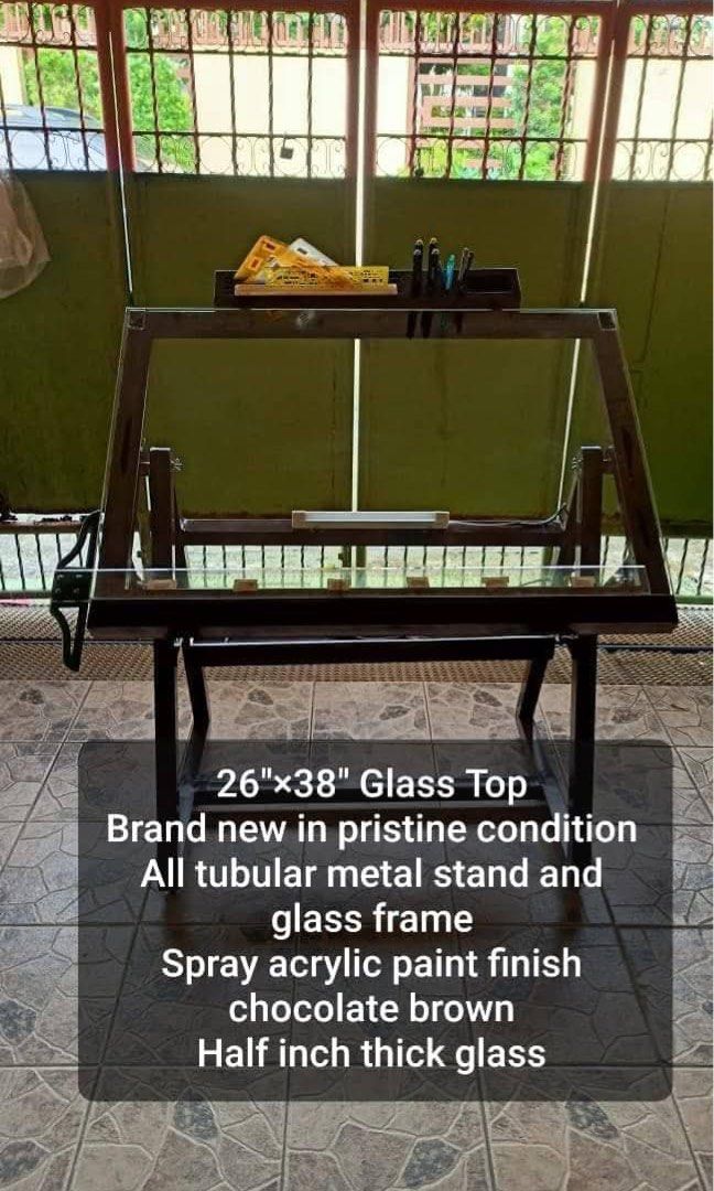 Glass Top Drafting Table (Category: Tables & Sets) located in Malolos. Submitted by clairo04 (Listing ID 1439584699, Image 2). Description: Adjustable Glass Top Drafting Table / Architect Desk – 24”x38” Description: Selling adjustable glass top drafting table bought from Luan’s Workshop. Originally bought for ₱10,300. Specifications: * 24” x 38” clear glass top * 10mm thick tempered glass * Adjustable tilt angle * Sturdy welded metal frame * With