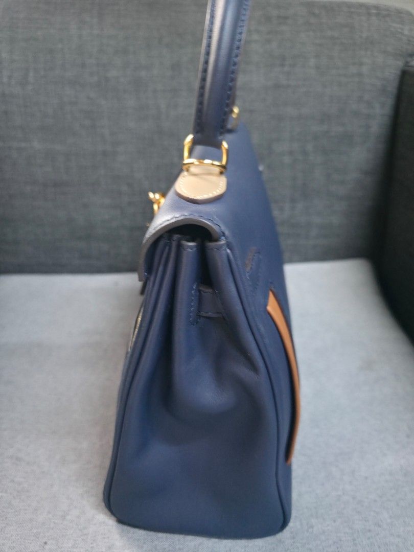 Blue Handbag with Gold Hardware (Category: Luxury Bags & Wallets) located in General Trias. Submitted by roselle2230 (Listing ID 1439517527, Image 2). Description: - Blue handbag with top handle - Gold-tone hardware - Tan leather accent - Secure clasp closure - Interior black pocket with blue zipper - Structured and sophisticated design - Suitable for various occasions.