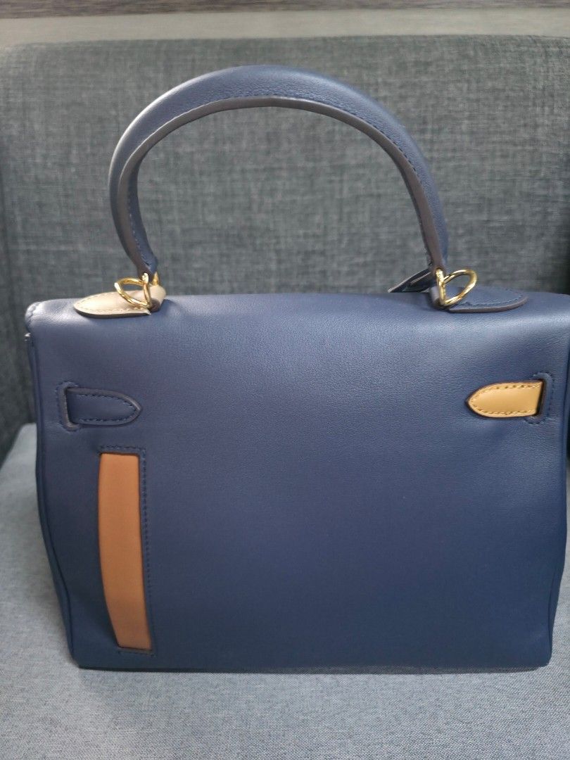 Blue Handbag with Gold Hardware (Category: Luxury Bags & Wallets) located in General Trias. Submitted by roselle2230 (Listing ID 1439517527, Image 3). Description: - Blue handbag with top handle - Gold-tone hardware - Tan leather accent - Secure clasp closure - Interior black pocket with blue zipper - Structured and sophisticated design - Suitable for various occasions.