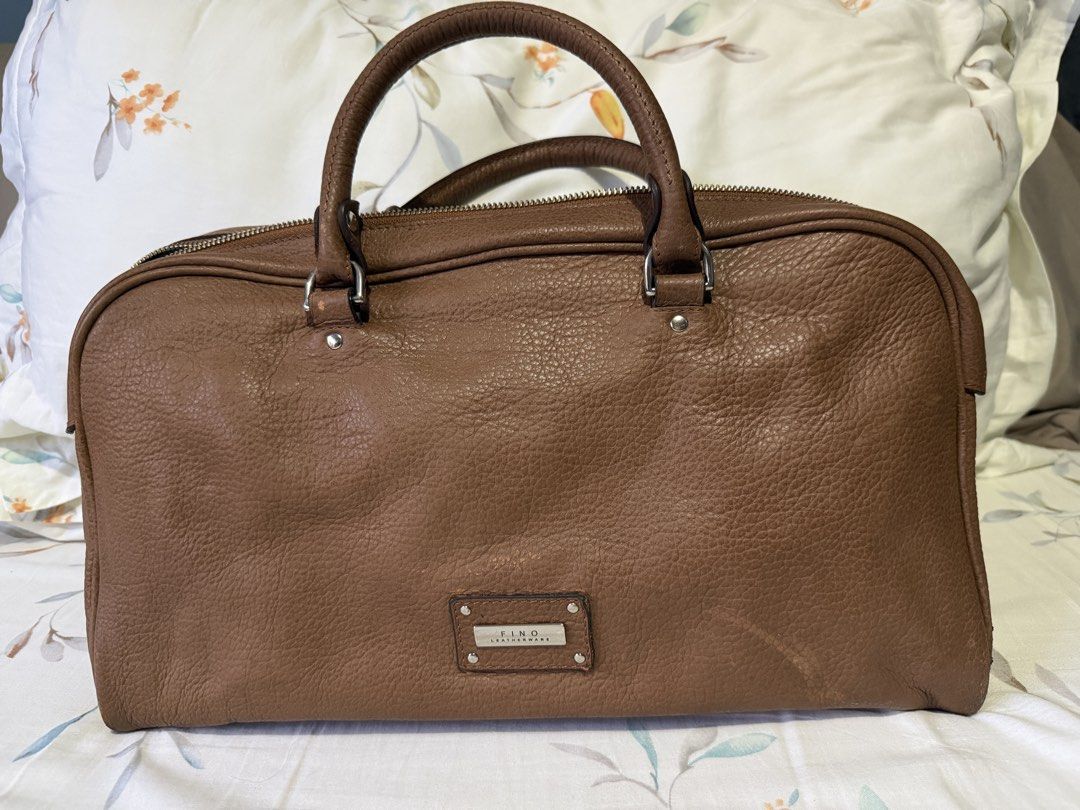 FINO Leatherware Brown Handbag (Category: Luxury Bags & Wallets) located in Paranaque City. Submitted by riannep (Listing ID 1439475856, Image 1). Description: - Brand: FINO Leatherware - Material: Genuine brown leather - Design: Top handle handbag - Closure: Zipper closure for main compartment and exterior pocket - Features: Multiple interior compartments for organization - Shape: Rectangular - Exterior: Textured leather finish - Details: Metal 