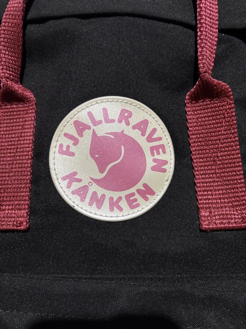 Fjallraven Kanken Backpack (Category: Backpacks) located in Lopez. Submitted by thrift.ni.roms22 (Listing ID 1439559793, Image 2). Description: Black Fjallraven Kanken backpack with red straps. Features a front pocket and a main compartment with a zipper closure. The Fjallraven logo is visible on the front. Includes adjustable shoulder straps and a top handle. The backpack has a classic design..