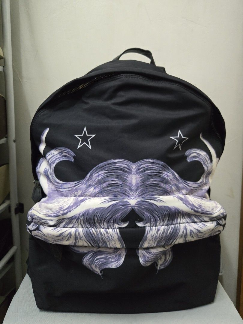 Givenchy Backpack （分類：手袋及銀包）位於 Hong Kong。 由 keish1802 提交（商品編號 1439503883，圖片 1）。簡介： Black Givenchy backpack with a unique purple and white design. Features a top handle and adjustable straps. Includes a front pocket with a zipper. The bottom of the backpack has a leather panel. Made in Italy.。