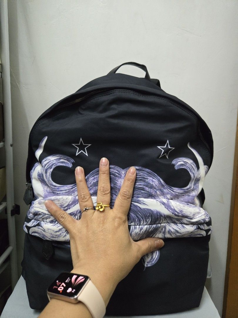 Givenchy Backpack （分類：手袋及銀包）位於 Hong Kong。 由 keish1802 提交（商品編號 1439503883，圖片 2）。簡介： Black Givenchy backpack with a unique purple and white design. Features a top handle and adjustable straps. Includes a front pocket with a zipper. The bottom of the backpack has a leather panel. Made in Italy.。