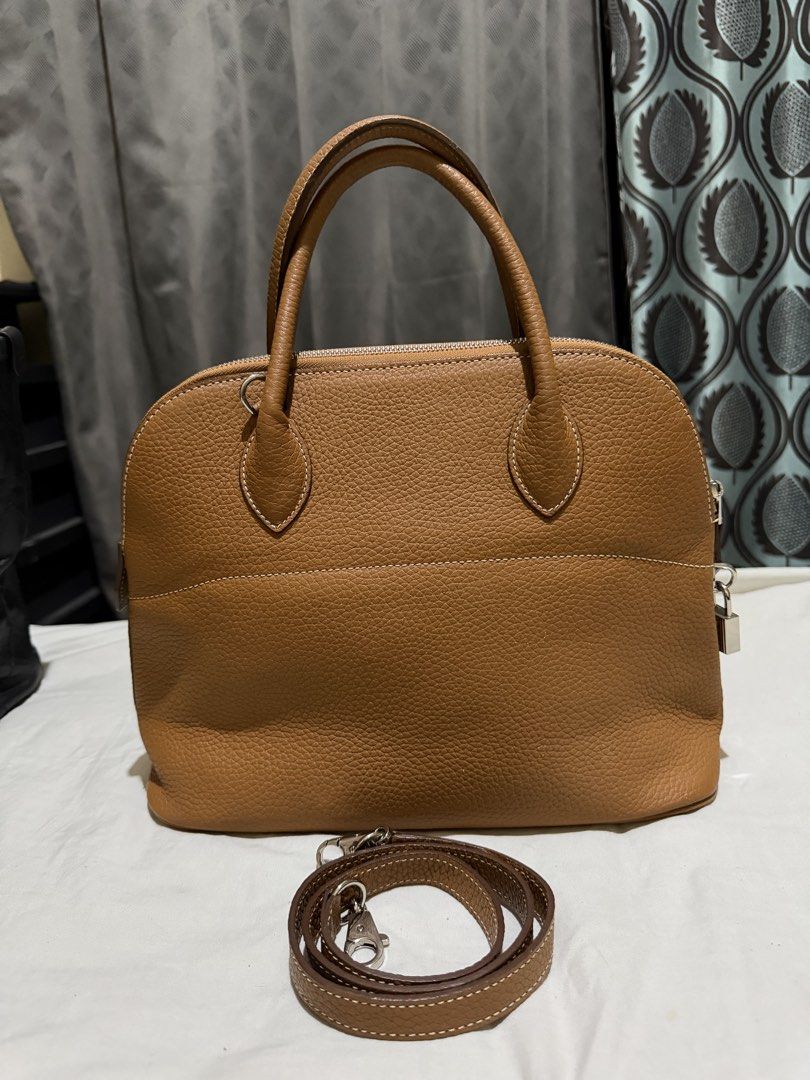 Hermès Paris Leather Handbag (Category: Luxury Bags & Wallets) located in Norzagaray. Submitted by royalearth.d73306 (Listing ID 1439566682, Image 2). Description: - Hermès handbag - Elegant tan color - Dome shape - Top handles and detachable shoulder strap - Silver-tone padlock and zipper closure - Spacious, lined interior .