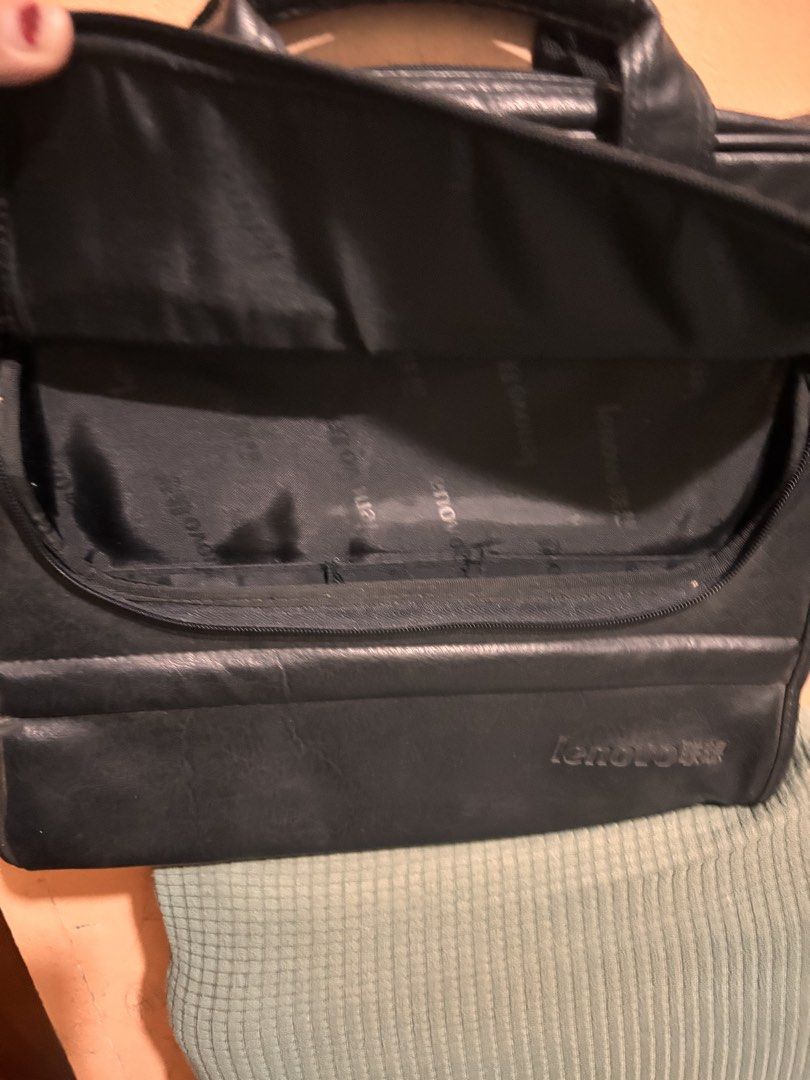 Lenovo Laptop Bag leather (Category: Laptop Bags & Sleeves) located in San Fernando. Submitted by ladychinita07 (Listing ID 1439453482, Image 3). Description: - Black Lenovo laptop bag - Multiple compartments for storage - Includes a handle and a shoulder strap - Features a zippered front pocket - Interior with Lenovo logo - Secure zipper closure - Made of a durable, leather-like material.