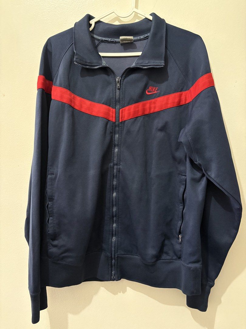 Nike Sportswear Track Jacket XL (Category: Coats, Jackets and Outerwear) located in Muntinlupa City. Submitted by take2mnl (Listing ID 1439529328, Image 1). Description: - Navy blue Nike track jacket - Red stripe accents - Size: XL - Full-length zipper - Two side pockets - Embroidered Nike logo - Collar and long sleeves.