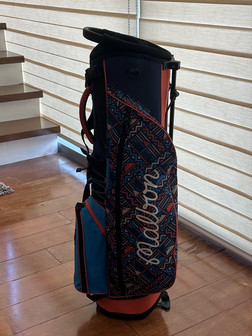 ORIGINAL MALBON Golf Caddy Stand Bag (Category: Golf) located in Makati City. Submitted by myclothesdefineme (Listing ID 1439469112, Image 2). Description: ORIGINAL Malbon golf stand bag with a unique patterned design. Features multiple compartments and a stand for easy use on the course. Includes a shoulder strap for convenient carrying. The bag has a navy, teal, and coral color scheme..
