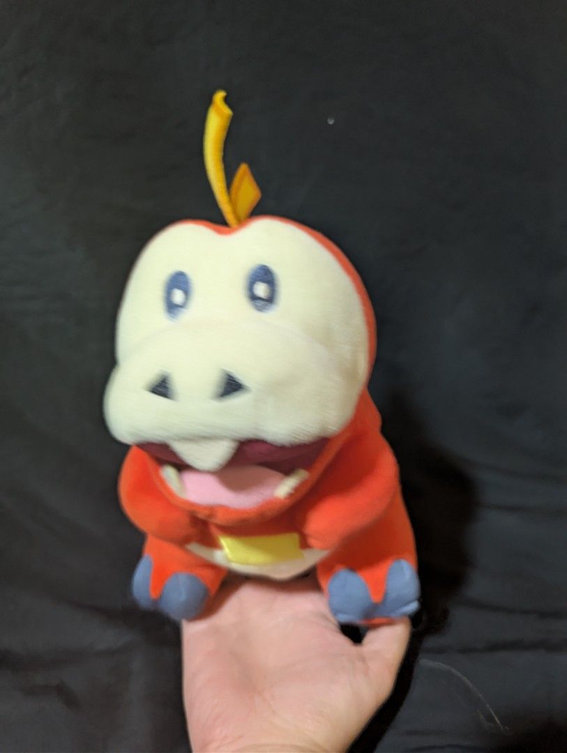Pokemon Fuecoco Plush Toy (Category: Plushies & Soft Toys) located in Malabon City. Submitted by apatoys (Listing ID 1439599197, Image 1). Description: - pokemon center Adorable Fuecoco plush! - Features: - Red body - White face - Blue feet - Yellow stem - Pink mouth - Perfect for Pokemon fans!.