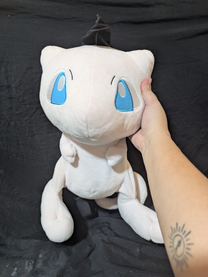 Pokemon Mew Plush Backpack (Category: Backpacks) located in Malabon City. Submitted by apatoys (Listing ID 1439598579, Image 1). Description: - Adorable Mew plush backpack! - Features a pink body with blue eyes and a black mohawk. - Adjustable black straps. - Zippered compartment on the back. - Perfect accessory for Pokemon fans!.