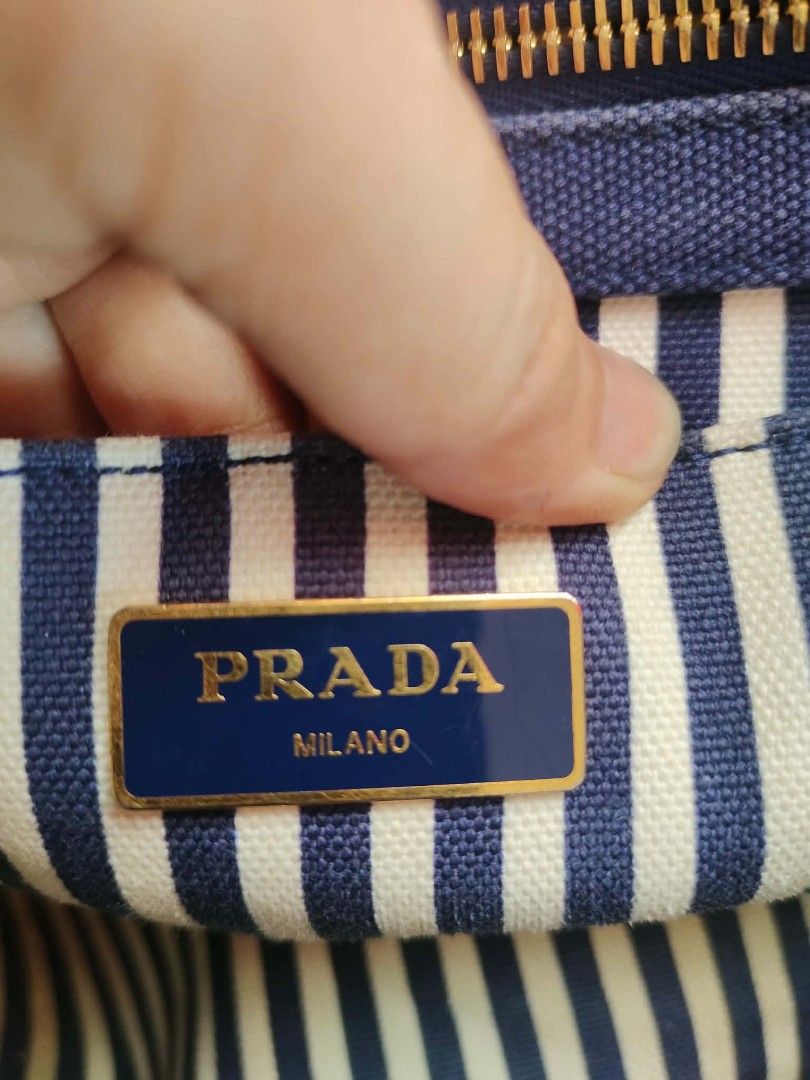 Prada Canvas Tote Bag denim canvass(dirt lining) (Category: Luxury Bags & Wallets) located in Cebu City. Submitted by tlisurplus (Listing ID 1439511899, Image 3). Description: - Authentic Prada tote bag - Blue canvas material - Striped interior lining - Detachable shoulder strap - Gold-tone hardware - Top handle - Zipper closure - Prada logo on front - Interior pocket with Prada label.