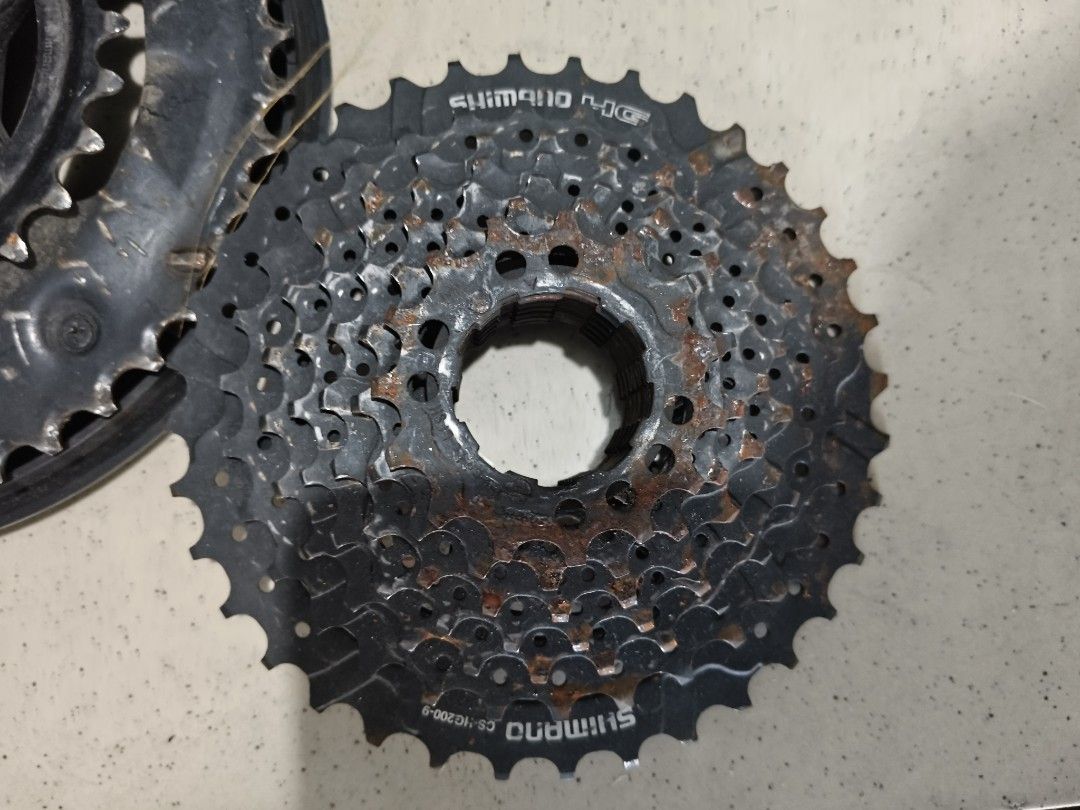 Shimano Cassette and Crankset (Category: Bicycles) located in Del Monte. Submitted by anitagalan89774 (Listing ID 1439421390, Image 1). Description: - Used Shimano cassette - Visible rust on cassette - Used Shimano crankset - Shimano logo on crankset - Single chainring on crankset - Likely for bicycle use.