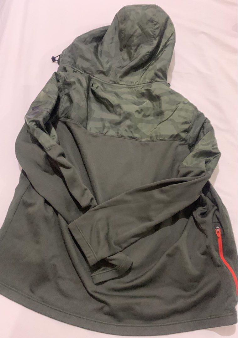 Under Armour Green Camo Hooded Jacket (Category: Coats, Jackets and Outerwear) located in Paranaque City. Submitted by vbvessentials (Listing ID 1439560981, Image 3). Description: Under Armour jacket features a green color with camo detailing on the hood and shoulders. It has a zip-up front, two side pockets, and a chest pocket, all with orange zippers. The jacket includes a hood with adjustable drawstrings. The size is Large. Flaw: the pull tab 