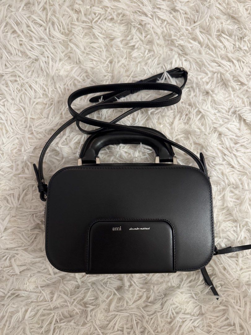 AMI Alexandre Mattiussi Black Handbag (Category: Luxury Bags & Wallets) located in San Pedro. Submitted by julio_sibulo (Listing ID 1439789062, Image 1). Description: - AMI Alexandre Mattiussi black handbag - Top handle and detachable shoulder strap - Front pocket with AMI logo - Clean interior - Rectangular shape, structured design - Silver-toned hardware.