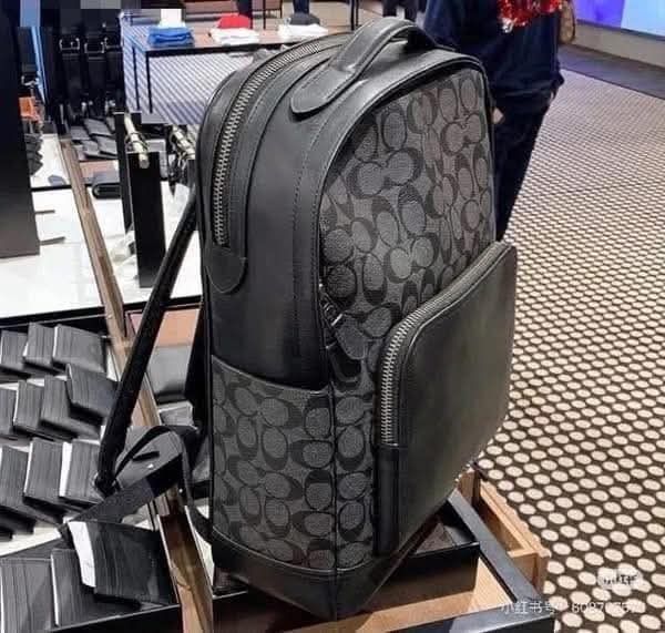 Coach Men's Signature Backpack (Category: Backpacks) located in Manila. Submitted by santosrich_419 (Listing ID 1439765237, Image 2). Description: - Authentic Coach backpack - Dark grey color with signature Coach pattern - Made of leather - Front pocket for easy access - Top handle for carrying versatility - Adjustable shoulder straps for comfort - Secure zipper closure - Features the Coach logo.