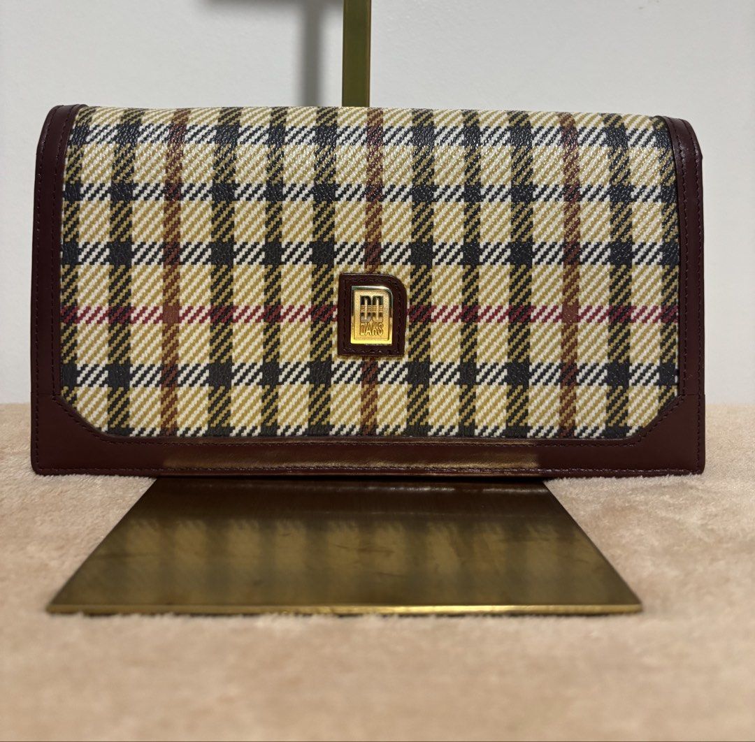 DAKS London Long Wallet Clutch (Category: Wallets & Card holders) located in Pasig City. Submitted by talaversify (Listing ID 1439796914, Image 1). Description: •DAKS London house check long wallet clutch in signature plaid with gold-toned logo plaque •Coated canvas body with premium deep burgundy/maroon leather trim with matching wristlet pull-strap •Spacious and convertible for everyday long wallet or a handheld clutch or a wristlet bag •Can fi