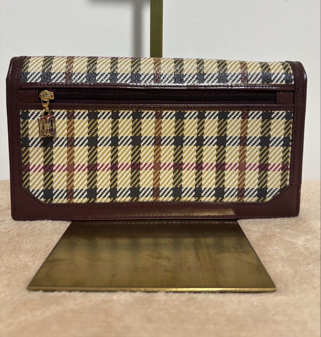 DAKS London Long Wallet Clutch (Category: Wallets & Card holders) located in Pasig City. Submitted by talaversify (Listing ID 1439796914, Image 2). Description: •DAKS London house check long wallet clutch in signature plaid with gold-toned logo plaque •Coated canvas body with premium deep burgundy/maroon leather trim with matching wristlet pull-strap •Spacious and convertible for everyday long wallet or a handheld clutch or a wristlet bag •Can fi