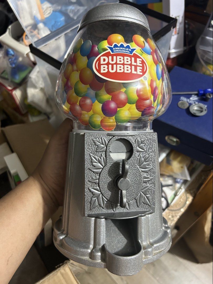 Dubble Bubble Gumball Dispenser Machine (Category: Kids Toys) located in Paranaque City. Submitted by zac.sei (Listing ID 1439642602, Image 1). Description: - Dubble Bubble gumball machine - Clear globe filled with colorful gumballs - Silver-colored metal base - Features a coin slot - Dispensing mechanism included - Base marked "CHINA".