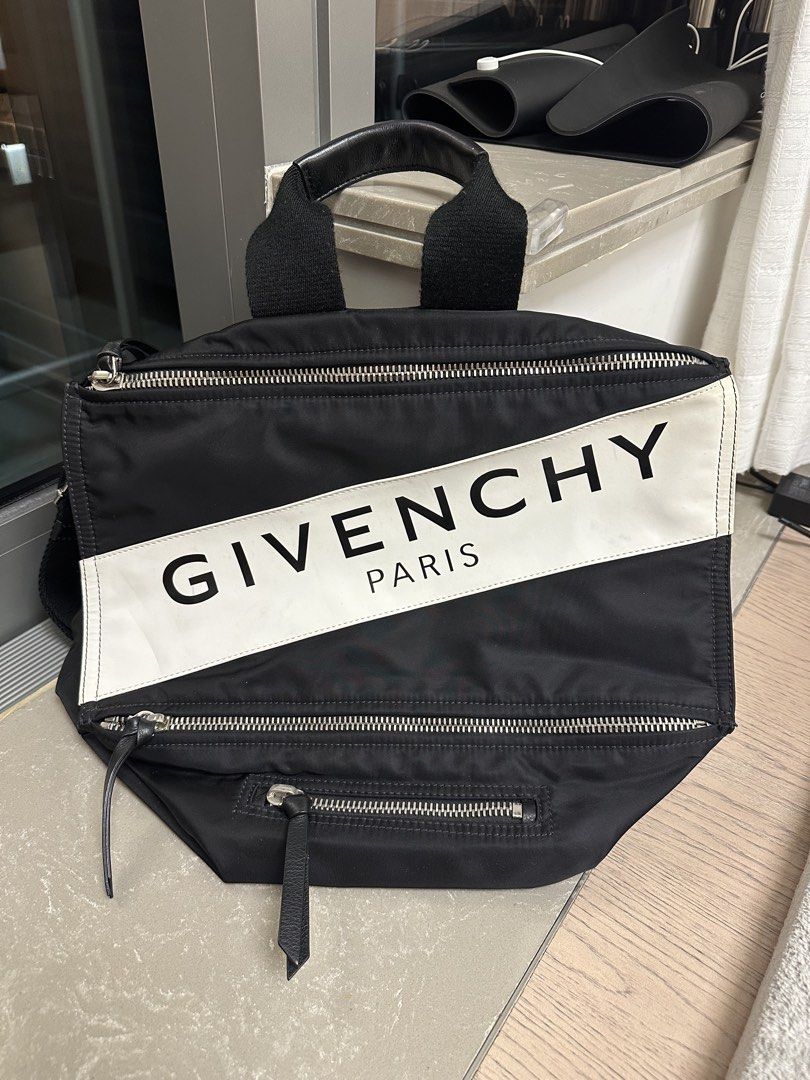 Givenchy Paris Black Pandora （分類：手袋及銀包）位於 Hong Kong。 由 shunsei 提交（商品編號 1439763314，圖片 1）。簡介： Black Givenchy Paris backpack with a white diagonal stripe. Features multiple zippered compartments and a top handle. Includes a detachable shoulder strap for versatile carrying options. The bag's design incorporates a sleek, modern aesthetic with the brand's logo prominently displayed.。