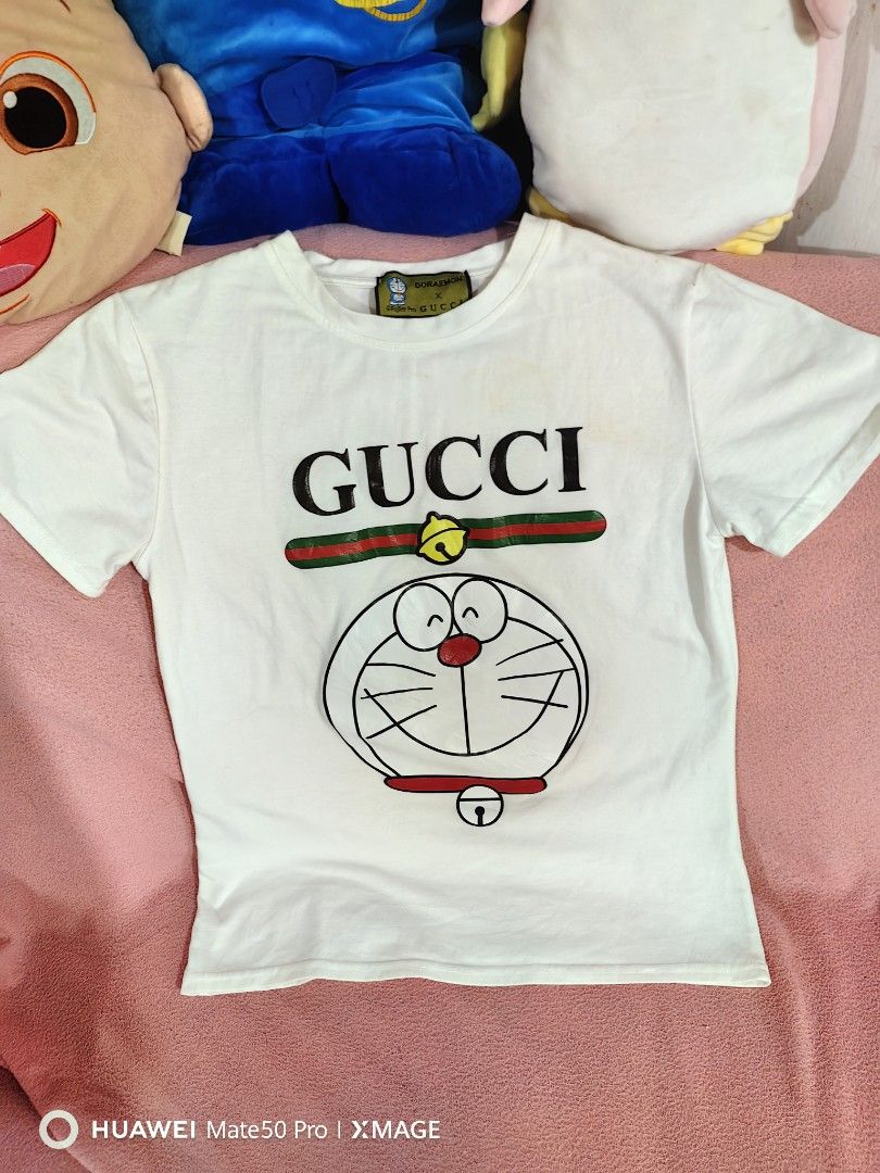 Gucci Doraemon T-shirt (Category: Luxury Apparel) located in Villasis. Submitted by mysticforest.bb2b4b (Listing ID 1439615720, Image 1). Description: - Authentic Gucci T-shirt - Features a Doraemon graphic - Classic white color - Short sleeves and round neckline - Gucci logo prominently displayed - Includes the iconic green and red stripe detail - Made from a lightweight material.