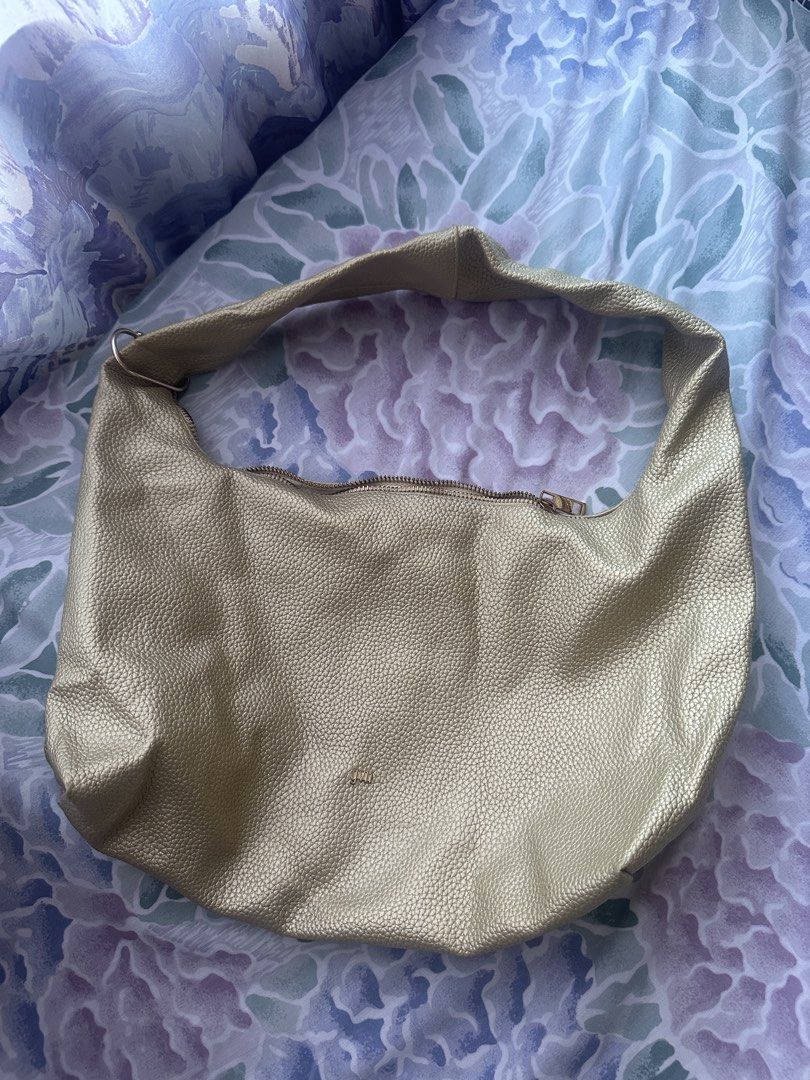 GVN Gold Hobo Bag Medium (Category: Luxury Bags & Wallets) located in Cavite. Submitted by _mariposa.mnl (Listing ID 1439655731, Image 1). Description: - Gold-colored hobo bag - Secure zipper closure - Includes a small interior pocket - Stylish textured exterior - Features the brand "GVN" - with gold buckle on the handle for keychains - flaw: zipper is broken.