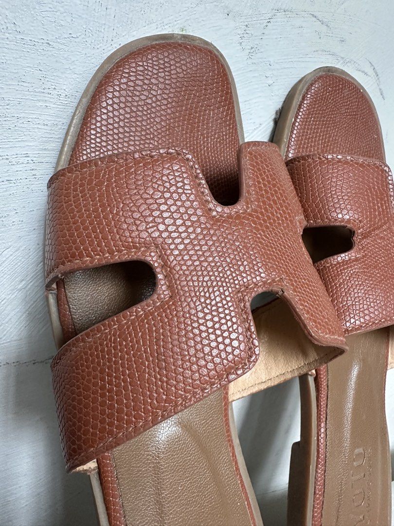 HERMES Oren Sandals Dupe - Brown Size 38 (Category: Flats & Sandals) located in Manila. Submitted by omelette.12 (Listing ID 1439694870, Image 2). Description: - YOTO brand sandals - Brown color - Features an 'H' design on straps - Textured appearance - Flat sole - Suitable for casual wear.