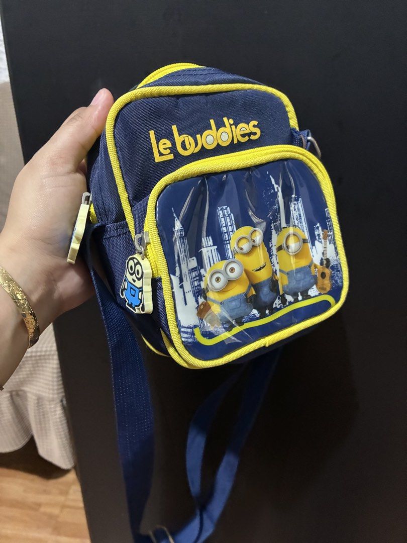 Le Buddies Minions Crossbody Bag (Category: Cross-body Bags) located in Quezon City. Submitted by grai25 (Listing ID 1439676355, Image 3). Description: - Le Buddies Minions Crossbody Bag - Fun Minions design - Main compartment with zipper - Front pocket with zipper - Blue strap - Yellow trim - Features "Le Buddies" text and Minions against a city skyline.