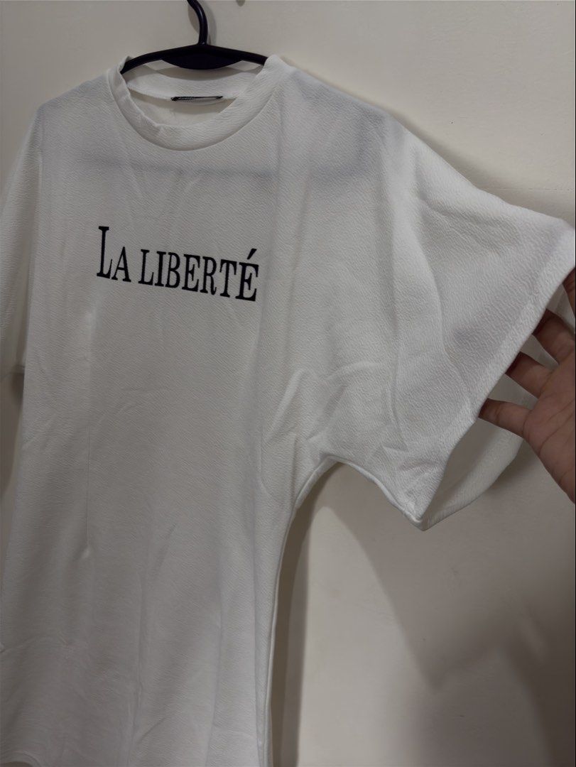 Lovito La Liberte White Dress (Category: Dresses) located in Quezon City. Submitted by mae_iggy (Listing ID 1439699257, Image 2). Description: - White dress with "La Liberte" print - Round neck - Short sleeves - Brand: Lovito - Size: 32M (EU 36, US 6) - Made in China.
