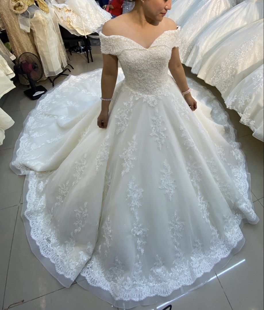 Off-Shoulder Ball Gown Wedding Dress (Category: Evening dresses & gowns) located in Legazpi City. Submitted by mblangcauon (Listing ID 1439657976, Image 1). Description: - Off-shoulder ball gown wedding dress - Features intricate lace detailing on bodice and skirt - Flowing, full skirt with lace trim - Color: White - Ideal for special occasions.